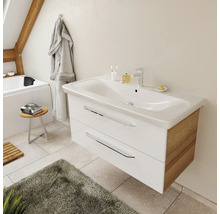 Meuble sous-vasque suspendu moderne avec façade blanche, côtés en bois et deux tiroirs dans une salle de bain lumineuse.
