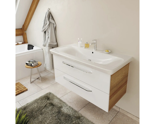 Meuble sous-vasque suspendu moderne avec façade blanche, côtés en bois et deux tiroirs dans une salle de bain lumineuse.