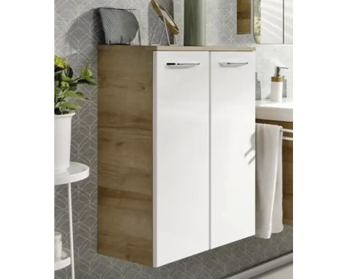 Meuble de salle de bain moderne avec deux portes blanches, corps en aspect chêne et poignées argentées devant un mur à motifs.