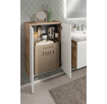 Armoire de salle de bain aspect bois, façades blanches, porte ouverte, panier à linge en tissu et étagère en verre.