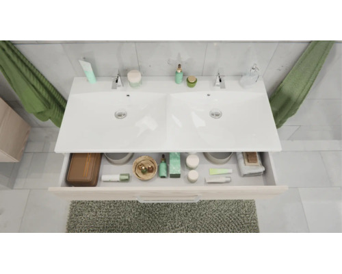 Vue de dessus d'un meuble double vasque avec un tiroir ouvert contenant divers articles de toilette et accessoires de salle de bain.