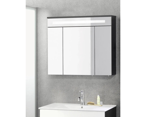 Armoire de toilette à trois portes avec éclairage LED au-dessus d'un lavabo blanc avec robinetterie chromée dans une salle de bains moderne.