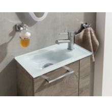Lavabo moderne avec vasque en verre blanc, meuble sous-vasque aspect bois, mitigeur chromé, distributeur de savon et crochet porte-serviette.