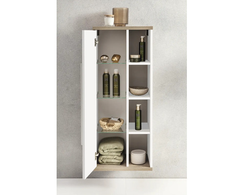Meuble de salle de bains suspendu étroit avec une porte et des compartiments ouverts, équipé d étagères en verre, de produits et de serviettes.