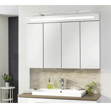 Großer Badezimmer-Spiegelschrank mit vier Türen und integrierter LED-Beleuchtung über einem weißen Waschbecken mit Holz-Waschtischplatte.