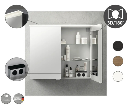 Armoire de toilette avec éclairage, prise intégrée et étagères en verre. Fabriqué en Allemagne. Une porte ouverte montre des articles de toilette.