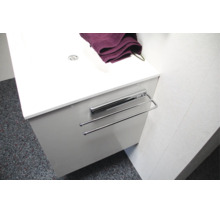 Porte-serviettes extensible en métal monté sur un meuble sous-vasque blanc.