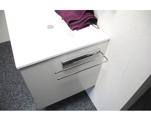 Porte-serviettes extensible en métal monté sur un meuble sous-vasque blanc.