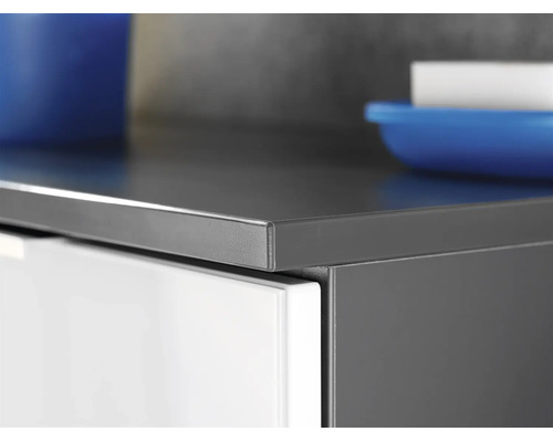 Vue détaillée du chant d'un plan de travail de cuisine anthracite sur un meuble bas blanc.
