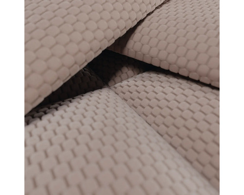 Nahaufnahme eines beigen Stoffes mit kleinteiliger Waffelstruktur oder Wabenmuster.