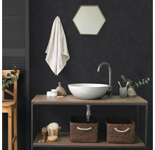 Salle de bains moderne avec vasque à poser ronde, mitigeur haut, miroir hexagonal et deux paniers de rangement tressés sur une étagère.