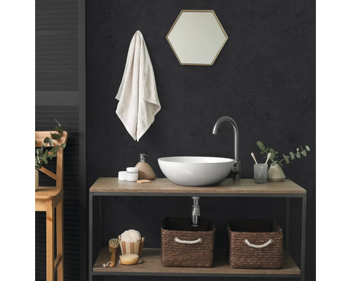 Salle de bains moderne avec vasque à poser ronde, mitigeur haut, miroir hexagonal et deux paniers de rangement tressés sur une étagère.