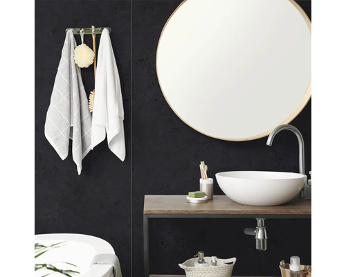 Salle de bain moderne avec miroir rond, vasque à poser blanche sur plan de toilette en bois et panneaux muraux sombres texturés.