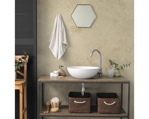 Salle de bain moderne avec vasque à poser blanche sur meuble en bois, robinet haut, miroir hexagonal et paniers de rangement.