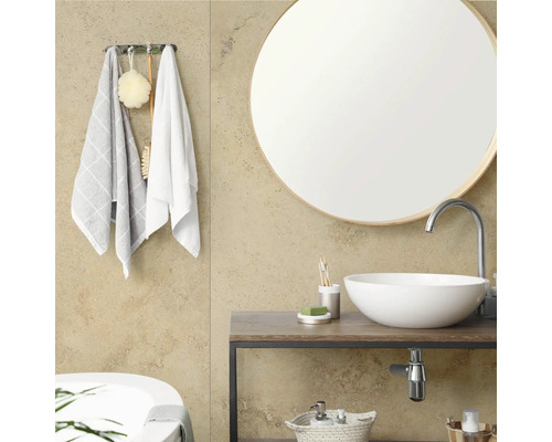 Salle de bain moderne avec miroir rond, vasque à poser sur un meuble en bois et crochets à serviettes avec accessoires.
