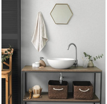 Salle de bains moderne avec vasque à poser blanche, robinet haut, miroir hexagonal et meuble sous vasque en bois avec paniers de rangement.