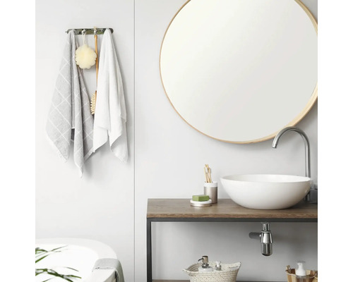 Modernes, helles Badezimmer mit rundem Spiegel, weißem Aufsatzwaschbecken auf Holzwaschtisch und Handtuchhalter mit Textilien.