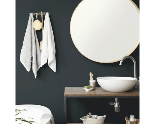 "Salle de bains moderne avec miroir mural rond, vasque  poser blanche sur plateau en bois et porte-serviettes."