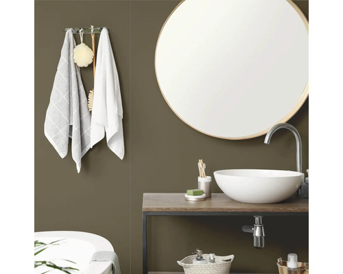 Salle de bains moderne avec mur vert olive, miroir rond avec cadre en bois, vasque à poser blanche sur meuble sous-vasque en bois et serviettes.