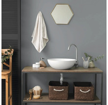 Salle de bain moderne avec vasque à poser blanche sur meuble sous-vasque en bois, robinet haut, miroir hexagonal et paniers tressés.