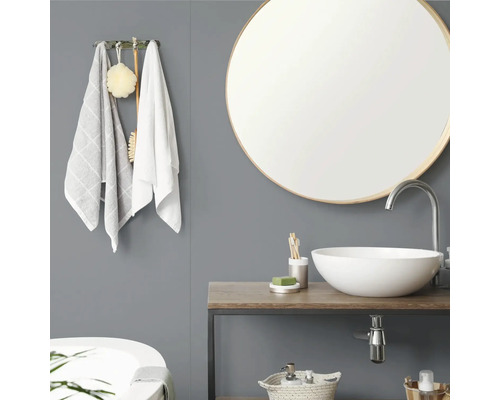 Salle de bain moderne avec miroir rond, vasque à poser blanche sur plan de toilette en bois, mur gris et patère avec serviettes.