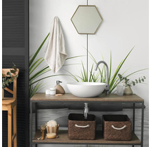 Salle de bain moderne avec vasque à poser ronde sur un meuble en bois, robinet haut, miroir hexagonal et paniers de rangement tressés.