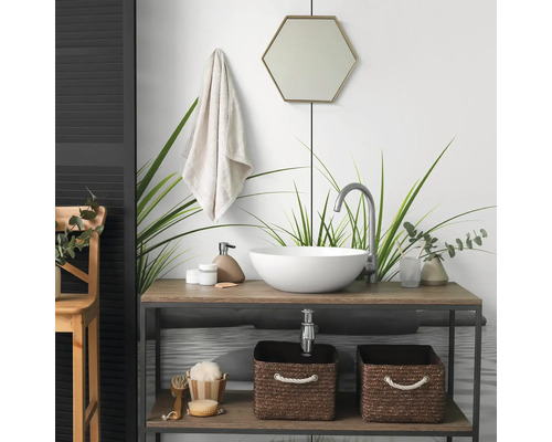 Salle de bain moderne avec vasque à poser ronde sur un meuble en bois, robinet haut, miroir hexagonal et paniers de rangement tressés.