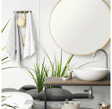 Salle de bains moderne avec miroir rond, vasque à poser blanche sur plan en bois et paroi en verre avec motifs d herbe et de galets.
