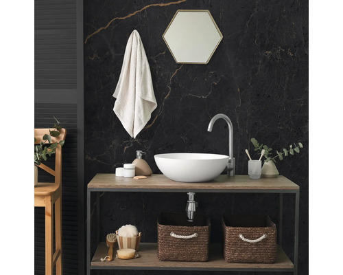 Salle de bains moderne avec vasque à poser blanche, plan en bois, mur en marbre sombre, miroir hexagonal et paniers de rangement tressés.