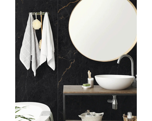 Salle de bain moderne avec carrelage mural aspect marbre noir, miroir rond et vasque blanche sur console en bois.