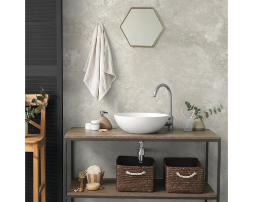 Modernes Badezimmer mit rundem Aufsatzwaschbecken auf einem Holzwaschtisch, Sechskantspiegel, Handtuch und Aufbewahrungskörben aus Geflecht.