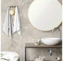 Modernes Badezimmer mit rundem Spiegel, weißem Aufsatzwaschbecken auf Holzkonsole, grauen Fliesen in Marmoroptik und Handtuchhalter.