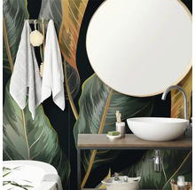 Salle de bain moderne avec papier peint intissé au motif de feuilles tropicales, vasque à poser blanche, miroir rond et meuble en bois.