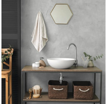 Salle de bains moderne avec vasque à poser blanche sur console en bois. Comprend un robinet courbé, un miroir hexagonal et des paniers tressés.
