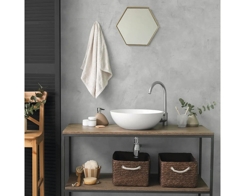 Salle de bains moderne avec vasque à poser blanche sur console en bois. Comprend un robinet courbé, un miroir hexagonal et des paniers tressés.