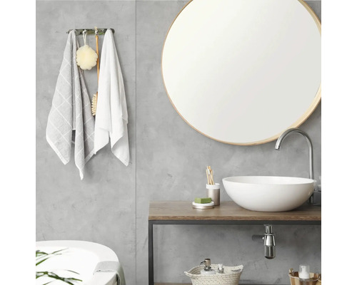 Salle de bains moderne avec miroir rond, vasque à poser blanche sur un plan de toilette en bois et mur gris aspect béton.