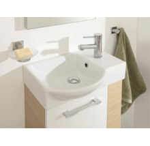 Salle de bains moderne avec lavabo compact, vasque en céramique blanche, meuble sous-vasque aspect bois, porte-savon et porte-serviette.