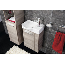 Salle de bain moderne avec meuble sous lavabo et armoire haute aspect bois, lavabo en céramique et carrelage sombre.