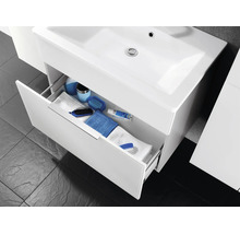 Meuble sous-vasque avec lavabo et un tiroir ouvert rempli de serviettes et de divers accessoires de salle de bains.