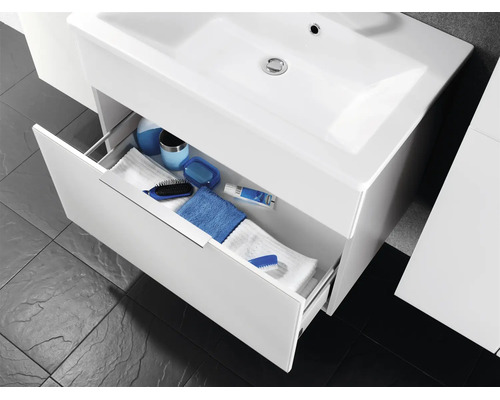 Meuble sous-vasque avec lavabo et un tiroir ouvert rempli de serviettes et de divers accessoires de salle de bains.