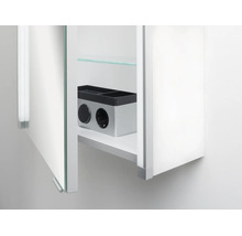 Vue intérieure d'une armoire de toilette avec prise de courant intégrée, interrupteur et étagère en verre.