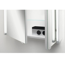 Armoire de toilette ouverte dans la salle de bains avec prise de courant intégrée, interrupteur et une tablette en verre.