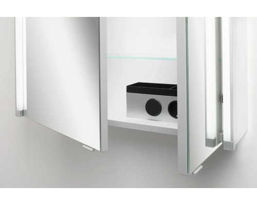 Armoire de toilette ouverte dans la salle de bains avec prise de courant intégrée, interrupteur et une tablette en verre.