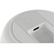 Detailansicht eines runden Power-Buttons und eines USB-C-Ladeanschlusses an einem elektronischen Gerät.