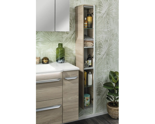 Salle de bains moderne avec meuble sous vasque aspect bois, armoire de toilette et colonne ouverte devant un papier peint à motif de feuilles.