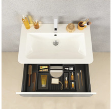 Lavabo blanc avec mitigeur et tiroir ouvert contenant des accessoires de salle de bains organisés tels que brosses, peignes et cosmétiques.