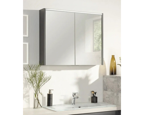 Armoire de toilette à deux portes au-dessus d'un lavabo clair dans une salle de bains moderne avec distributeur de savon et robinet.
