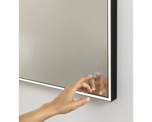 Beleuchteter Badezimmerspiegel mit schwarzem Rahmen und Touch-Sensor zur Steuerung der LED-Beleuchtung.