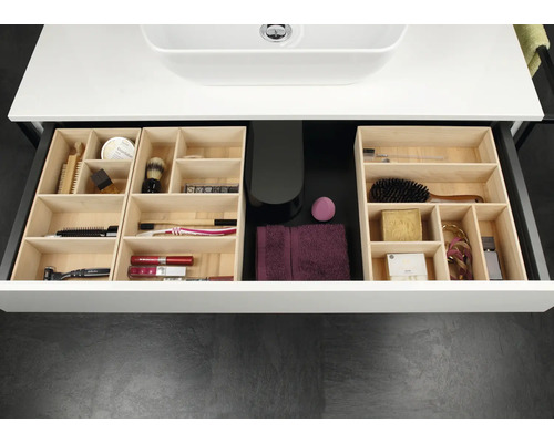 Tiroir de salle de bains organisé avec des inserts modulaires en bois clair contenant divers produits de soin et cosmétiques.