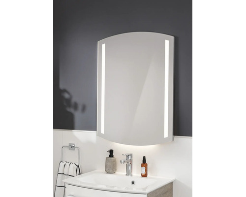 Miroir de salle de bain avec éclairage LED latéral et inférieur, forme bombée, monté au-dessus d'un lavabo dans une salle de bain moderne.